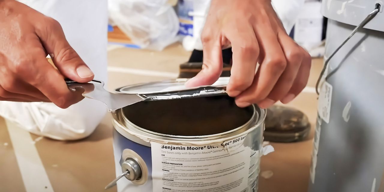 Painter opening a can of Benjamin Moore paint