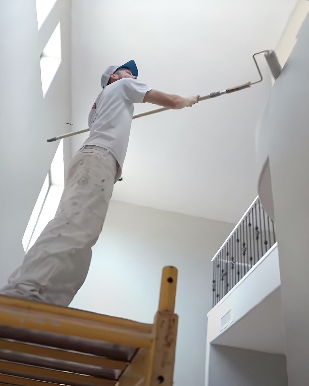 Painter on scaffolding rolling paint onto a tall wall