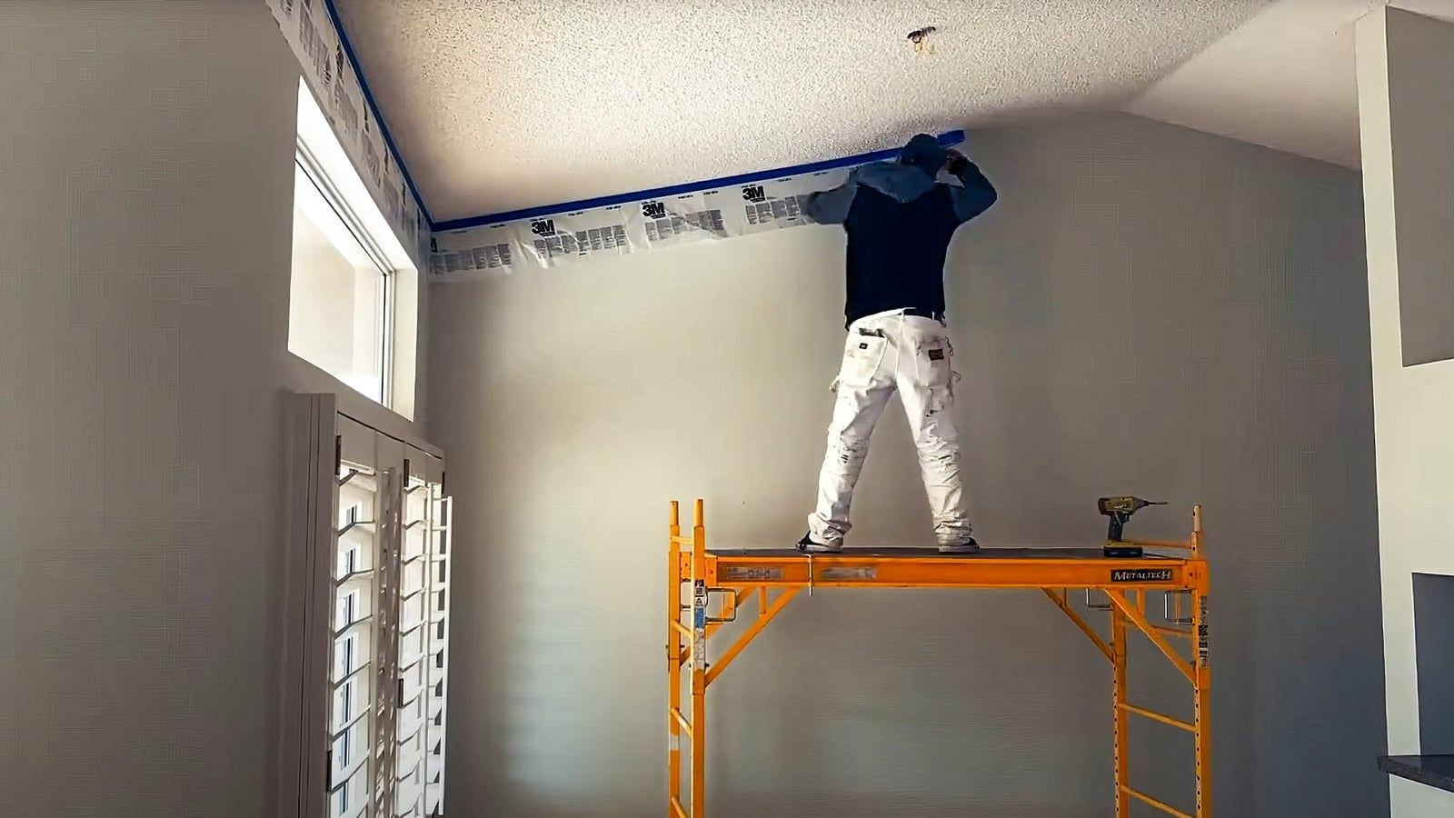 Painter on scaffolding painting a ceiling edge