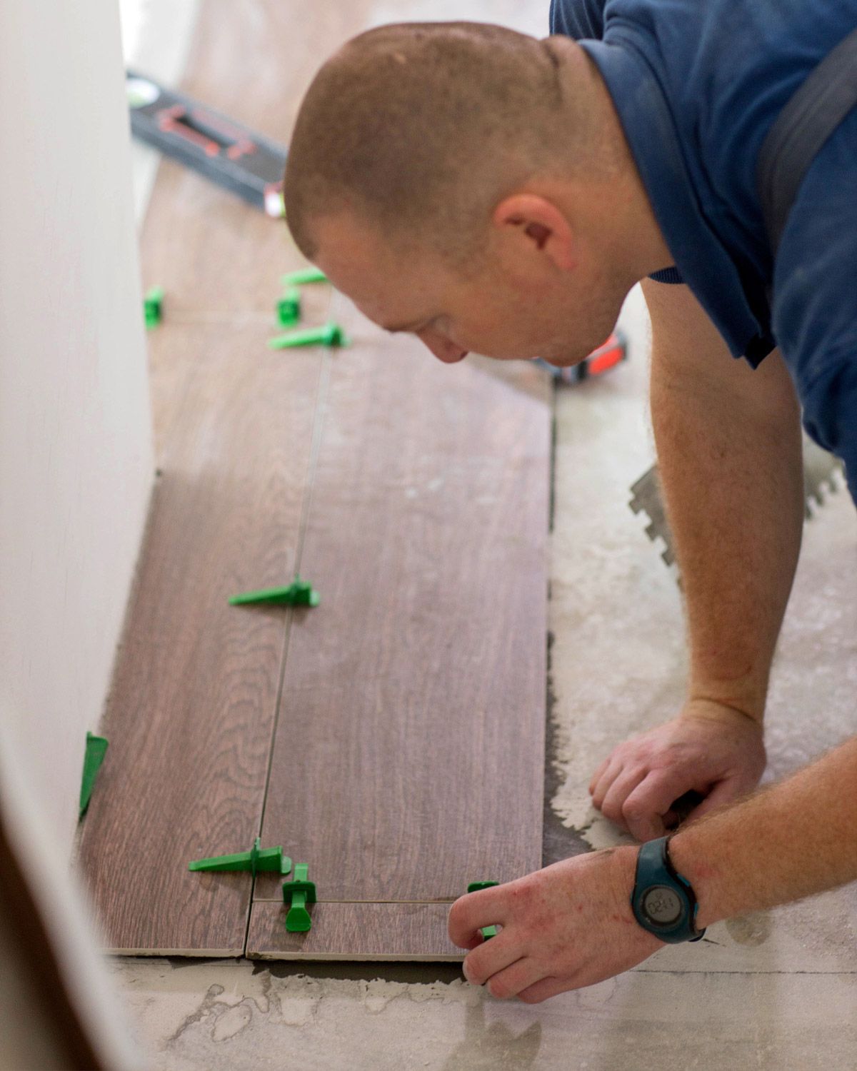 Installer laying wood-look plank floor with leveling clips