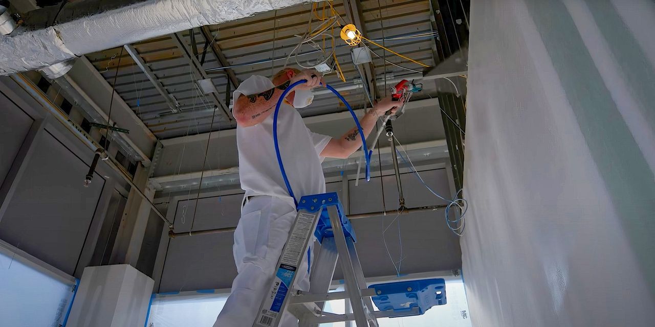 Painter spraying the ceiling of a commercial building from a ladder