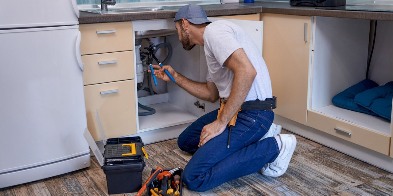 Handyman working under a kitchen sink cabinet