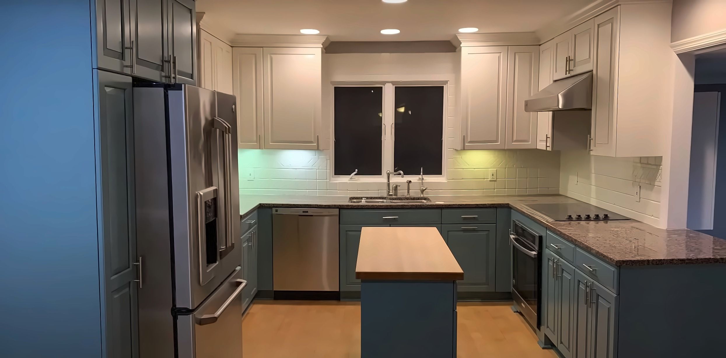 The same kitchen after: white upper cabinets, blue-gray lower cabinets and island
