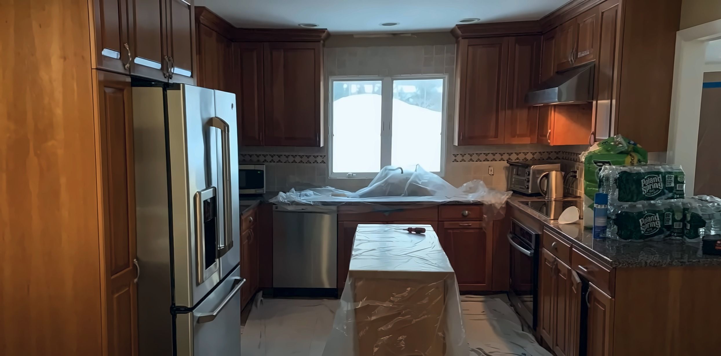 Kitchen before: cherry wood cabinets with the counters covered in plastic