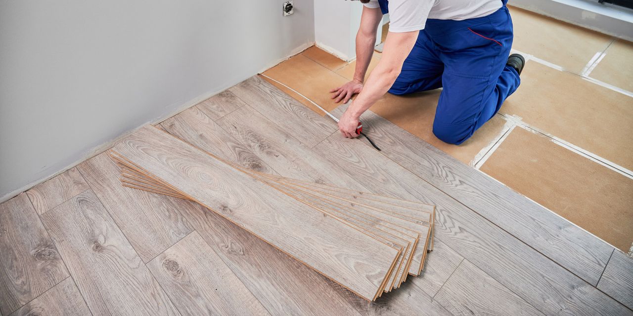 Installer measuring for the next row of laminate planks