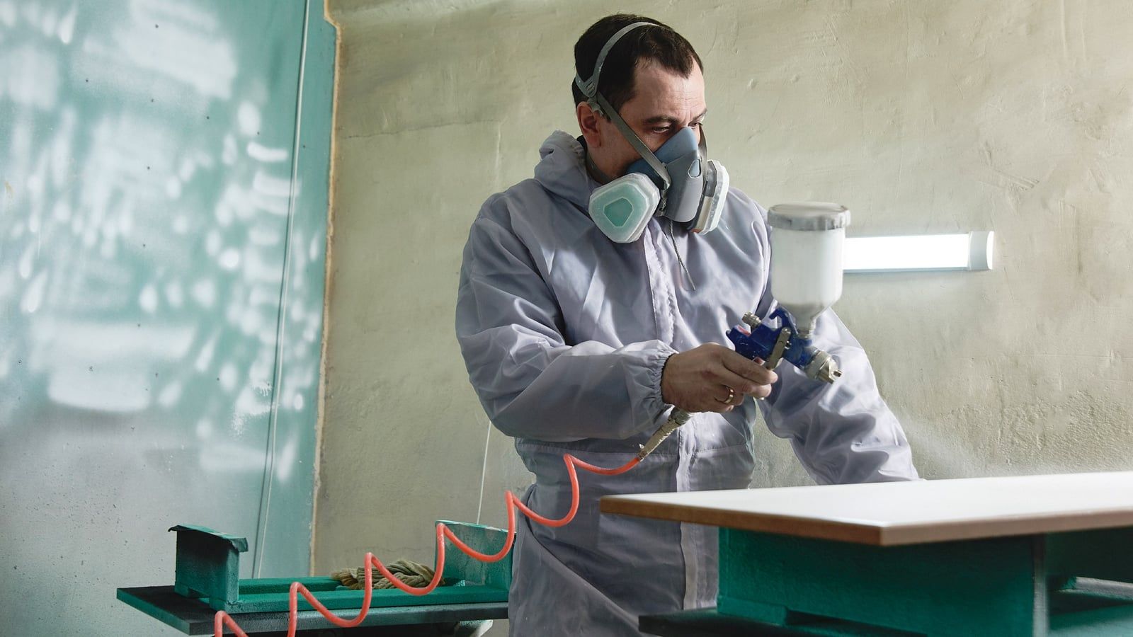 Painter spraying a cabinet door with a spray gun