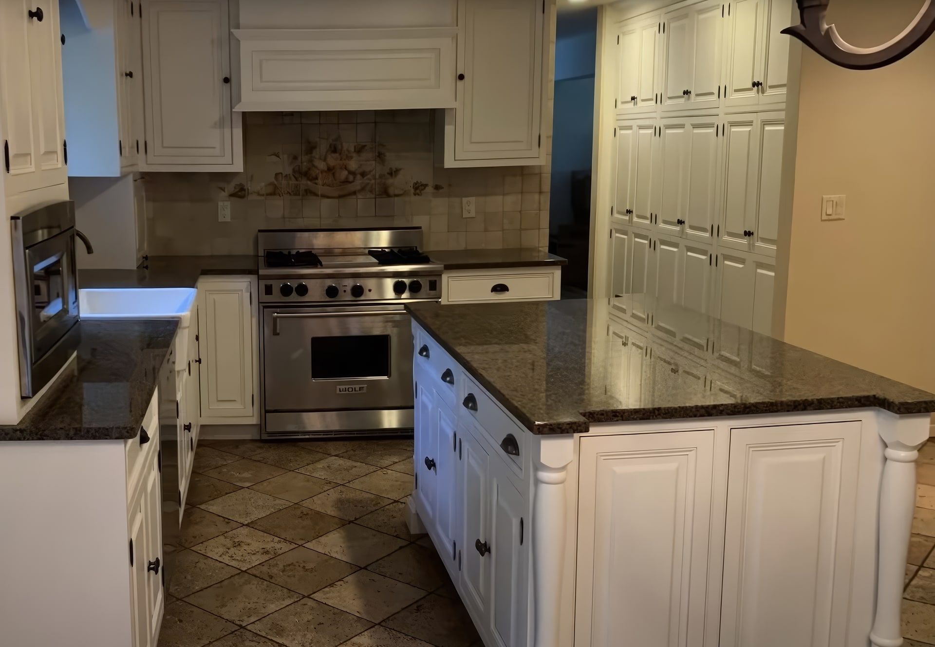 The same kitchen after: cabinets, island and pantry wall painted white