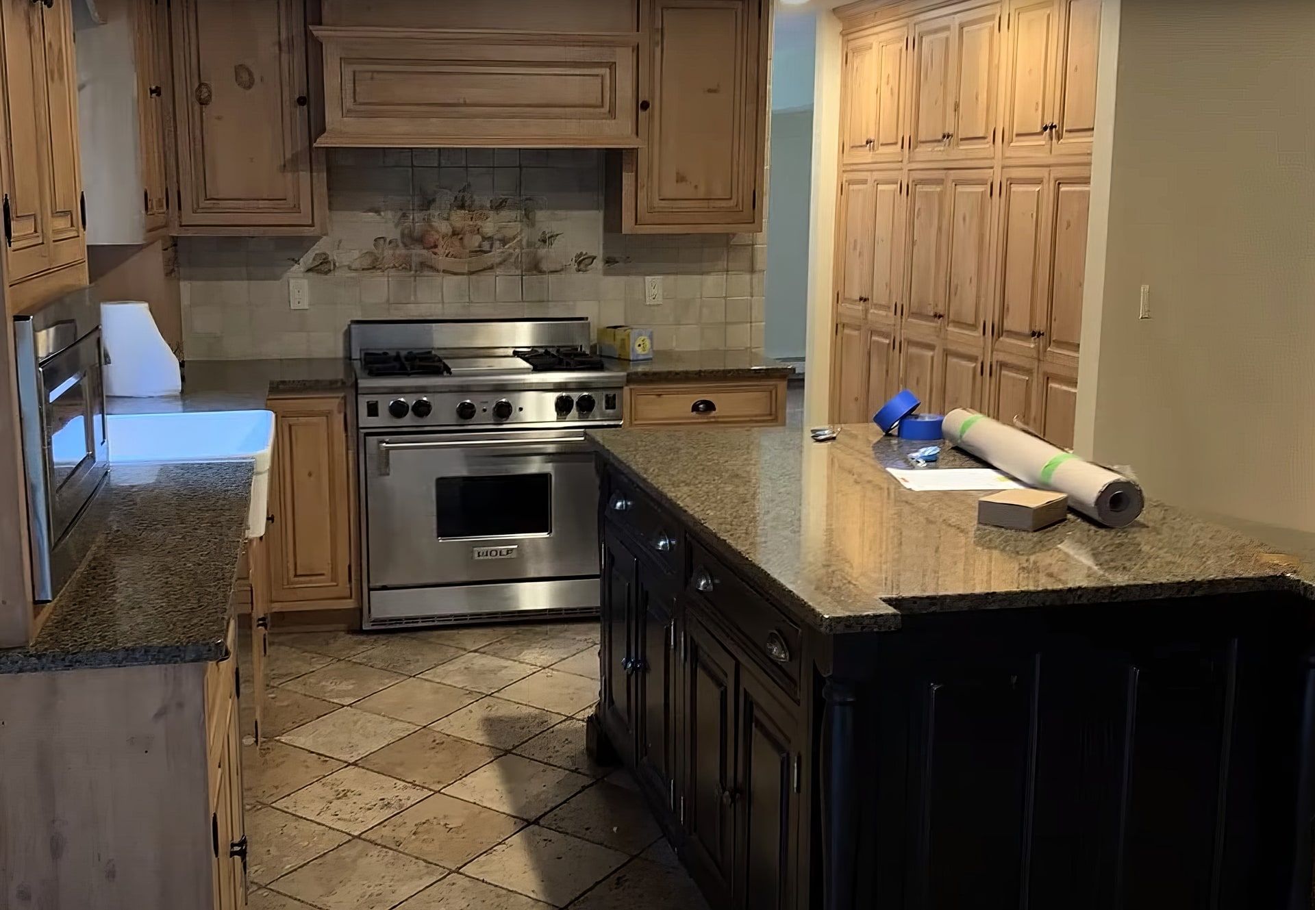 Kitchen before: knotty pine cabinets and a black island