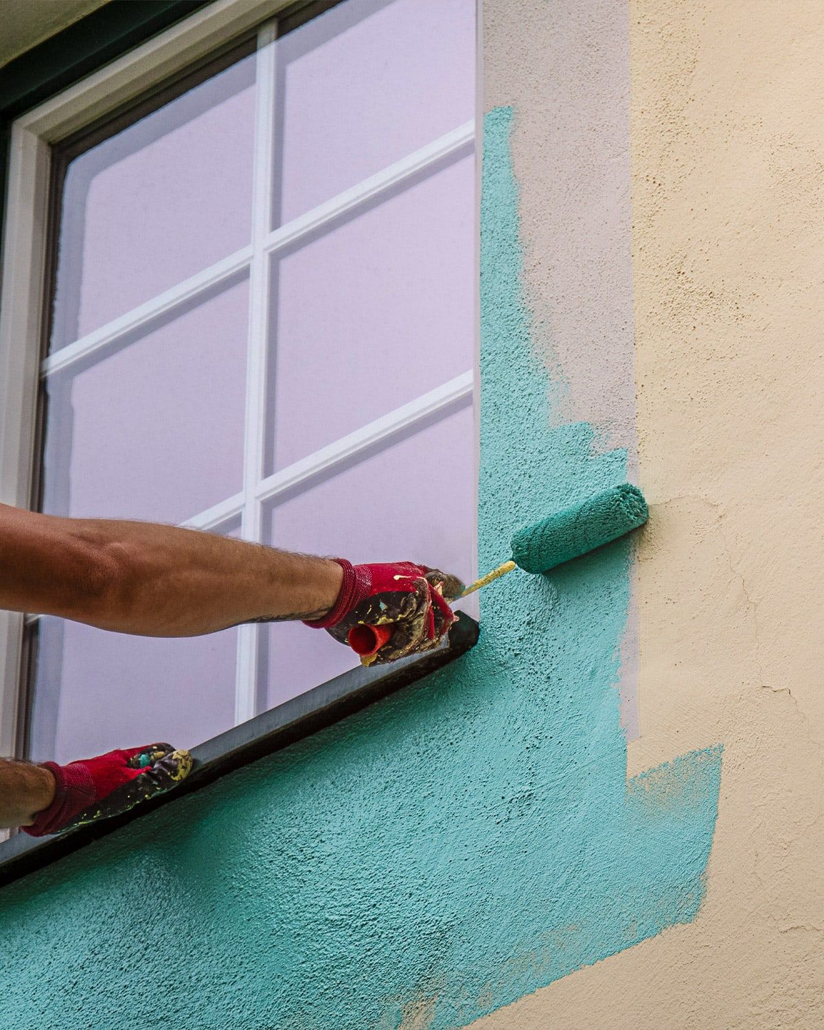 Painter rolling paint onto exterior stucco