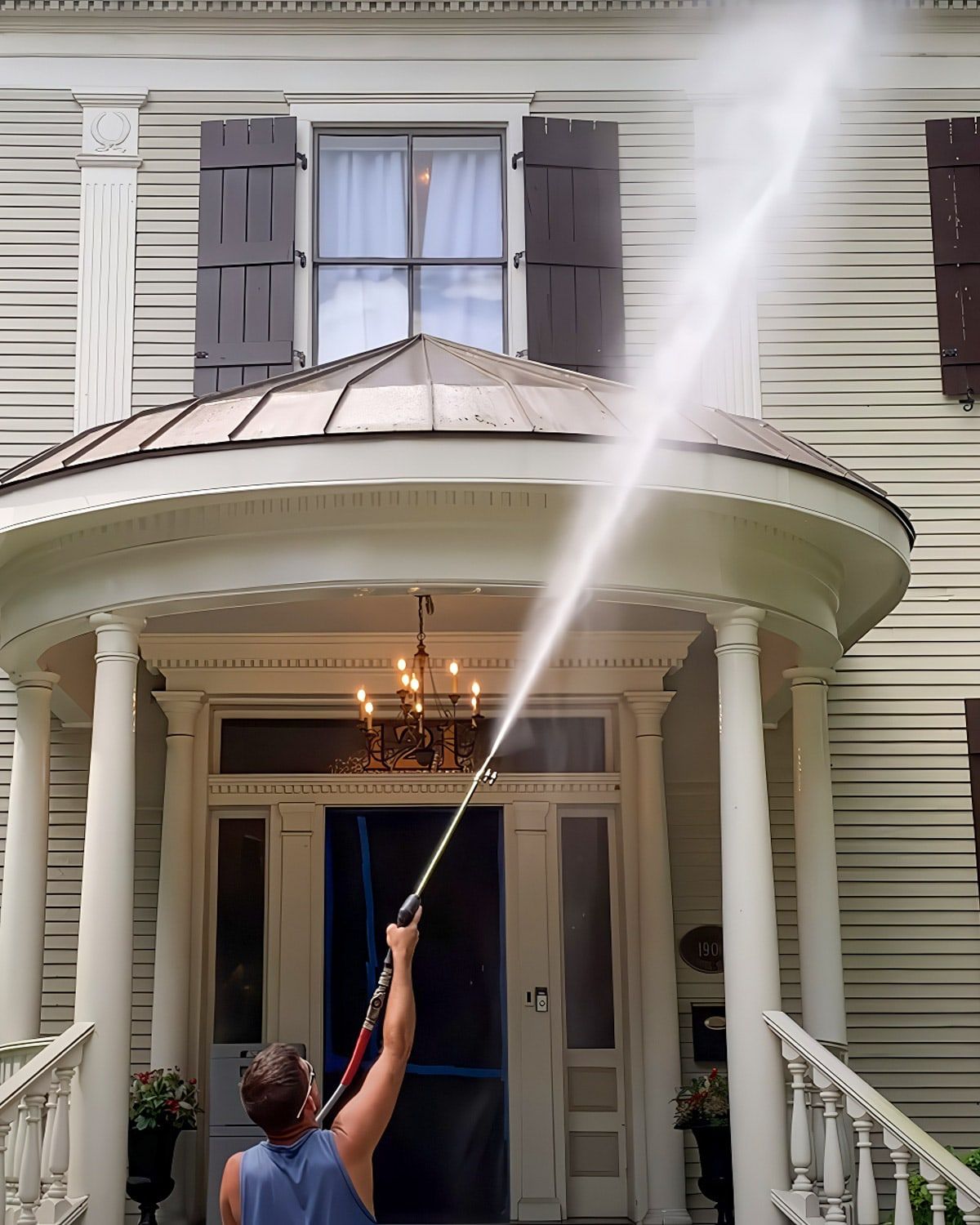 Pressure washing the front of a two-story house