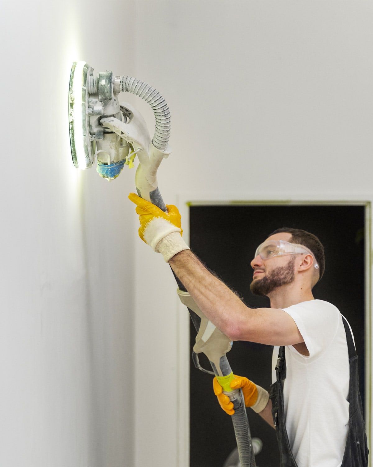 Sanding a wall with a power sander