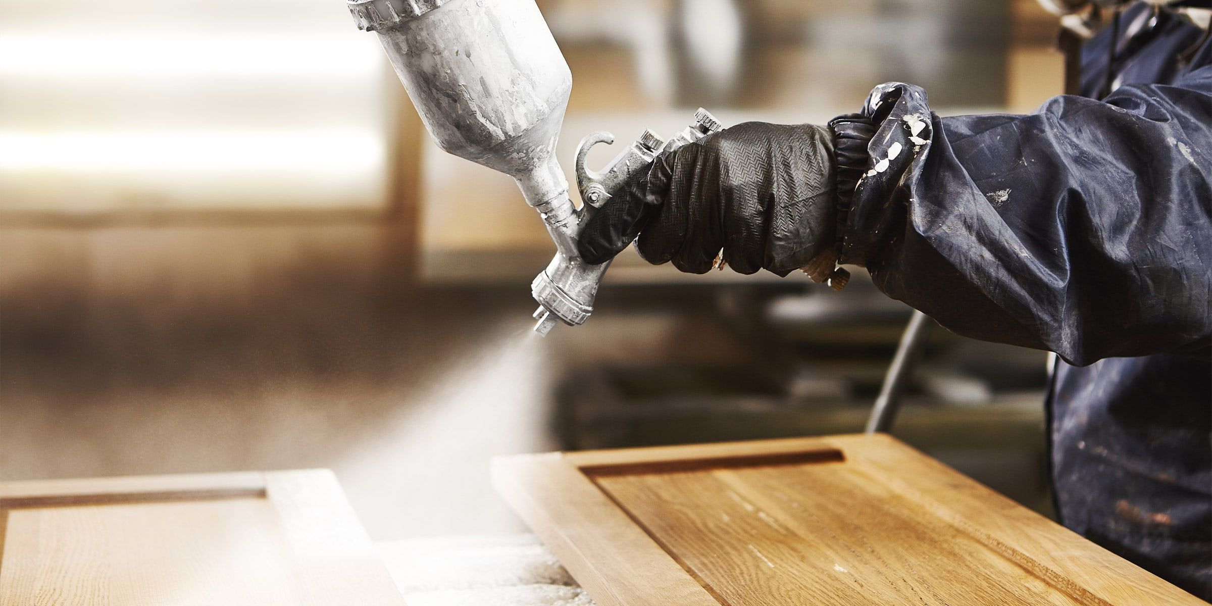 Close-up of a spray gun finishing a cabinet door
