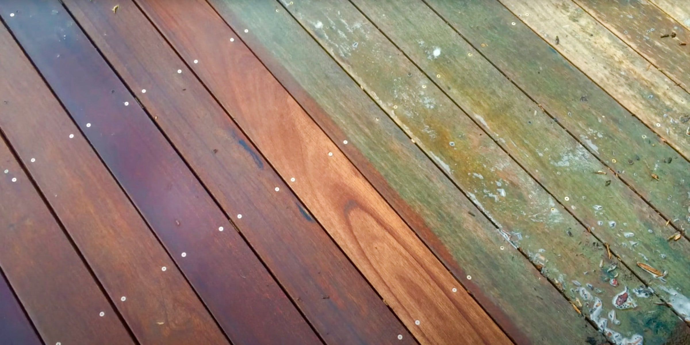 Deck boards half stained, showing the old weathered wood next to the new stain