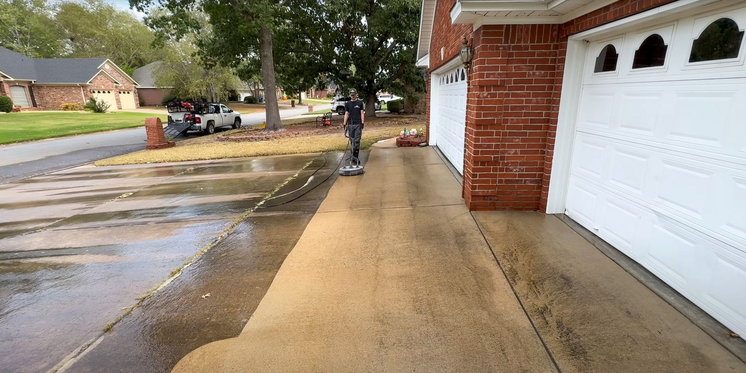 Driveway in front of a brick house being pressure washed