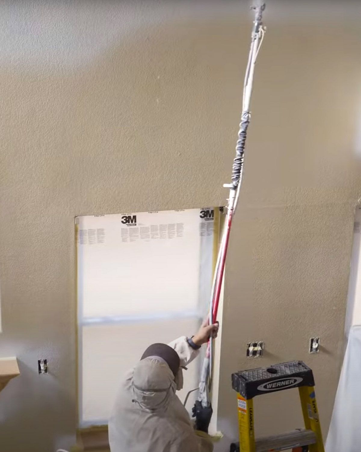 Painter spraying an interior wall with an airless sprayer