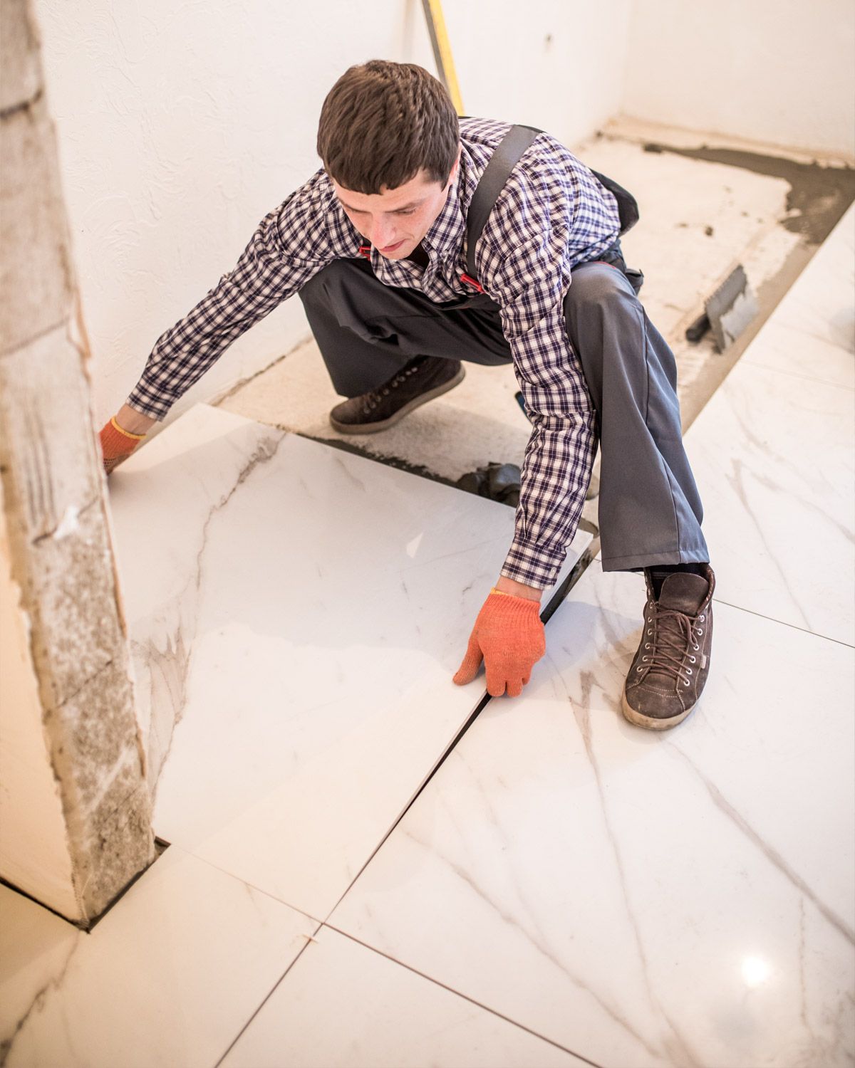 Installer laying large white floor tiles