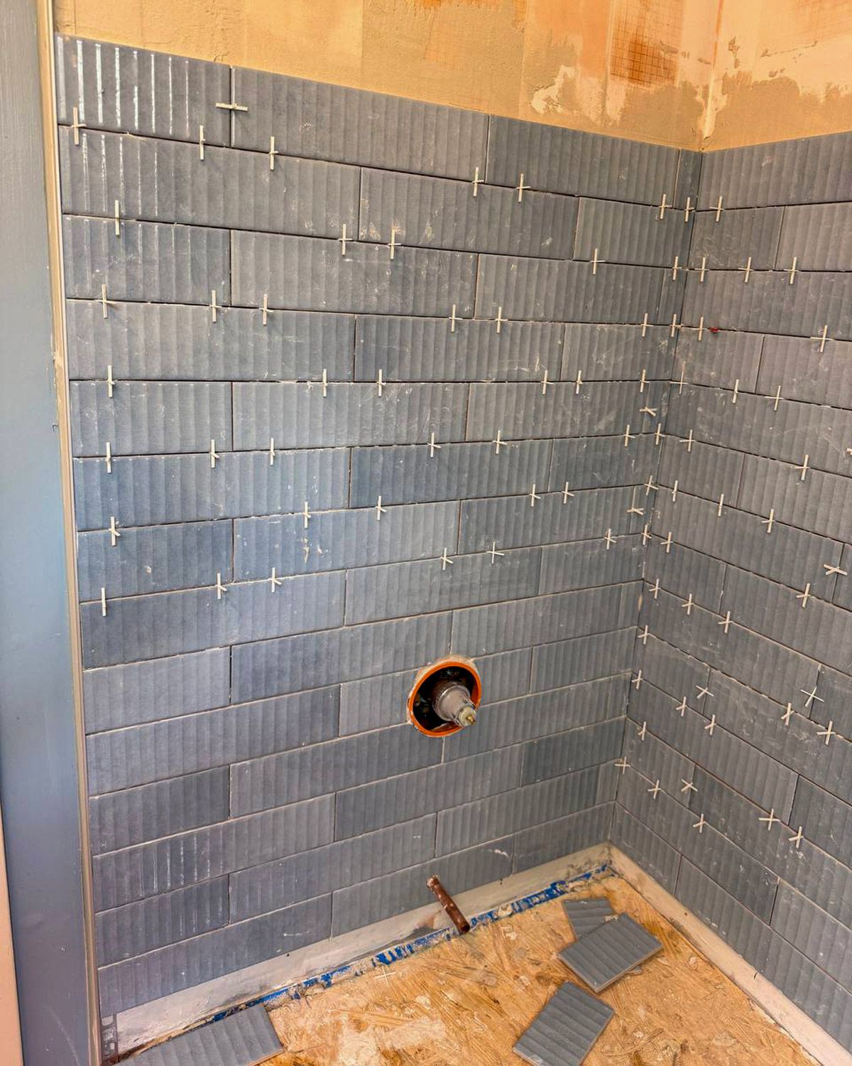 Shower wall tiled with blue subway tile