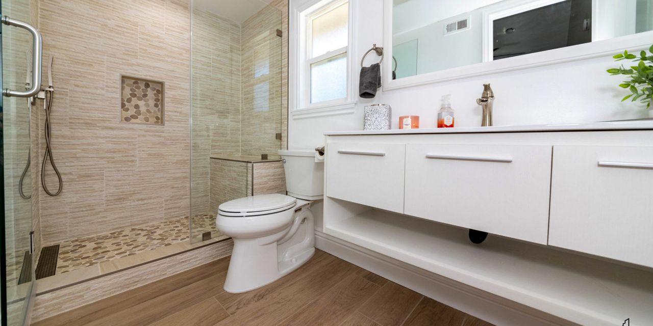 Finished bathroom with a tiled walk-in shower, glass panels and a pebble floor