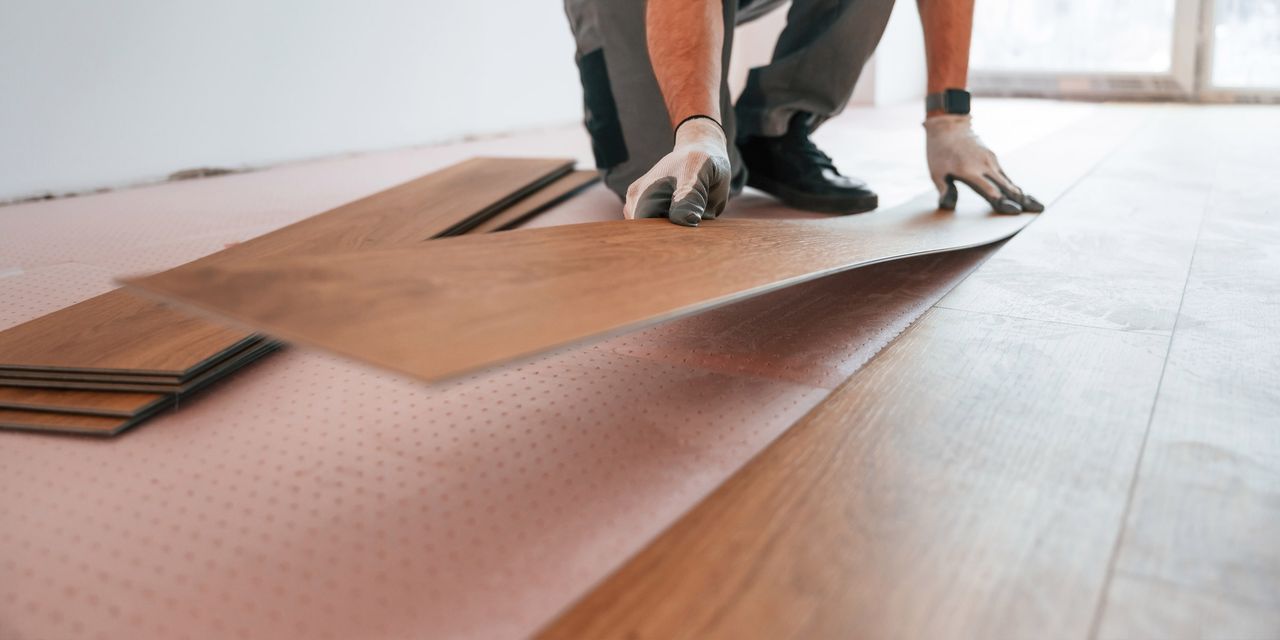 Installer laying a flexible vinyl plank over underlayment